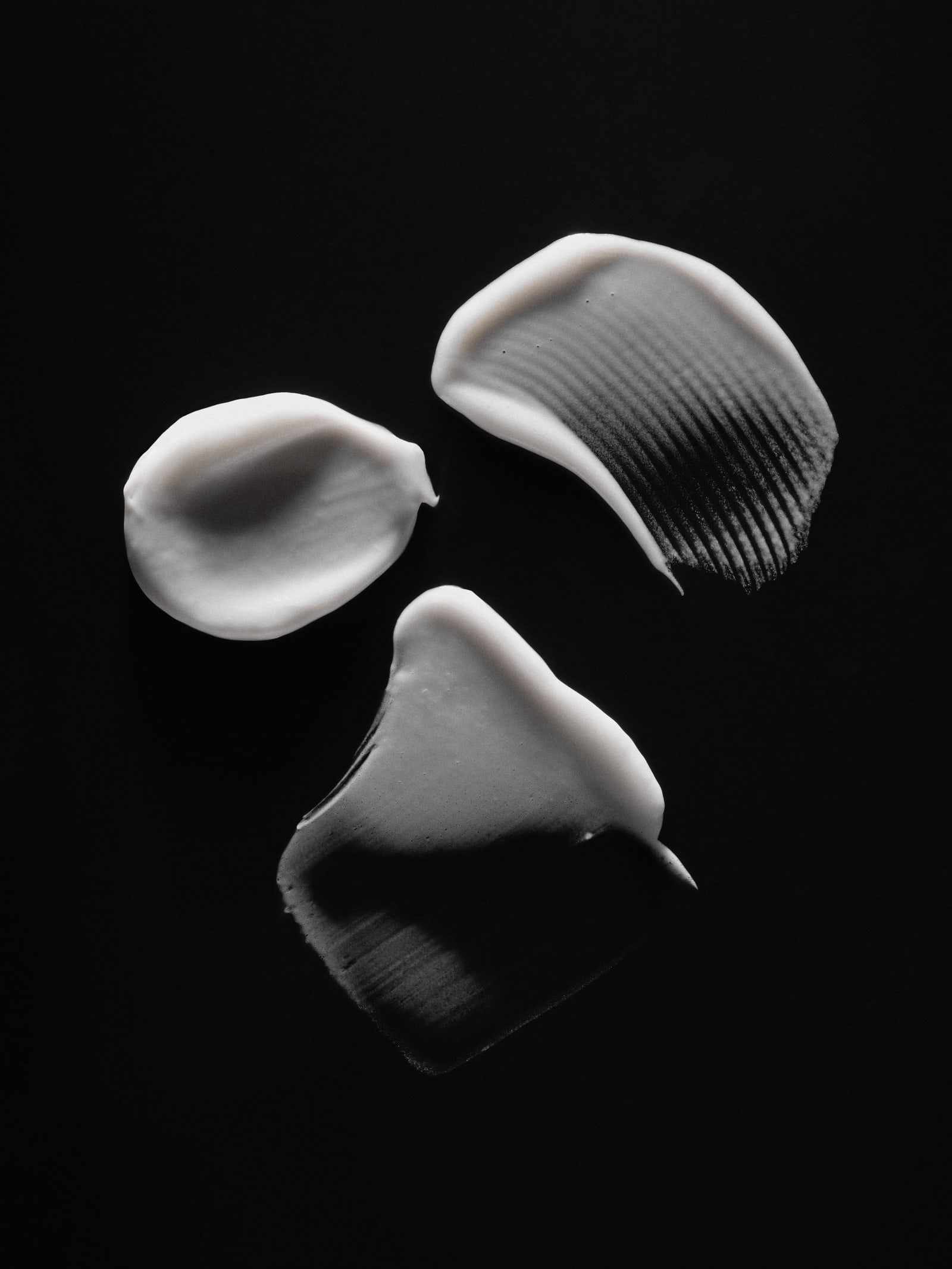 Close-up textures of RAWDOG skincare formulas on a black background