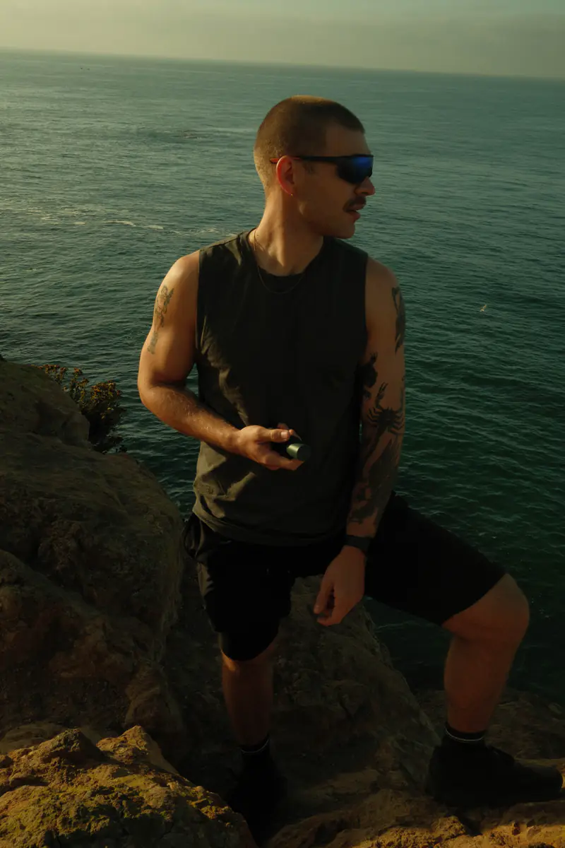 Man holding RAWDOG Hydrating Facial Cleanser on a Malibu cliff
